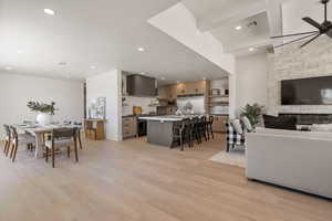 Living room with light wood finished floors, a ceiling fan, recessed lighting, and beam ceiling
