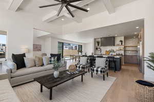 Living room featuring beamed ceiling, light wood-type flooring, ceiling fan, and recessed lighting