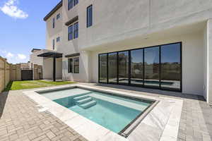 Rear view of property with a patio area, stucco siding, a fenced backyard, a pergola, and an in-ground hot tub