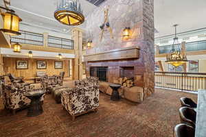 Carpeted living area featuring a high ceiling, a fireplace, and wood walls
