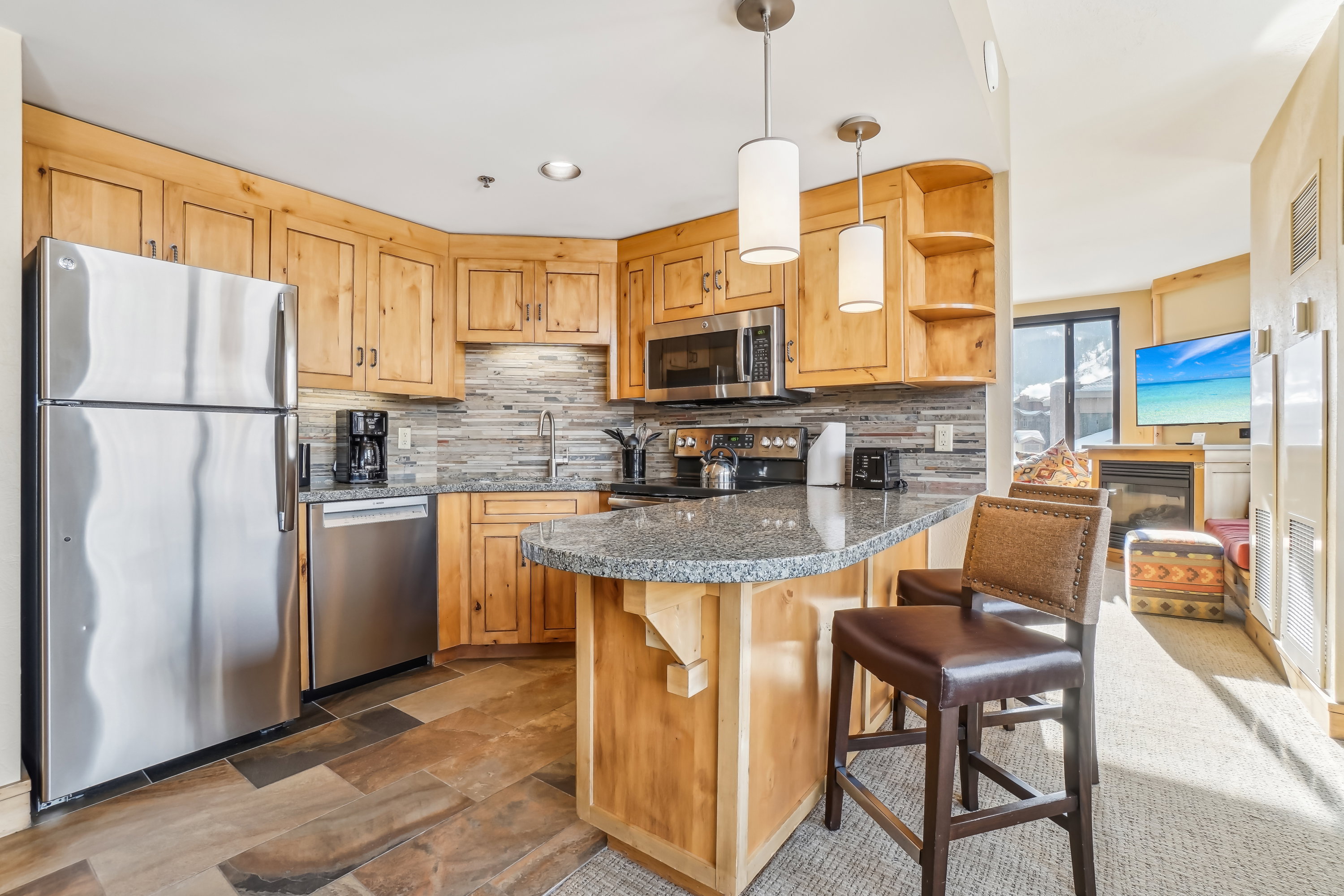 Kitchen featuring stainless steel appliances, a kitchen breakfast bar, decorative light fixtures, a peninsula, and decorative backsplash