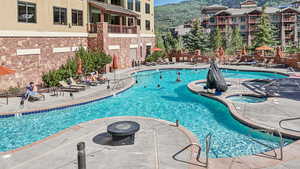 Community pool with a patio, a hot tub, and a mountain view