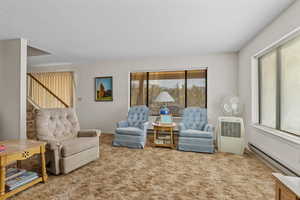 Living area with baseboard heating and carpet