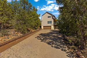 View of front of property featuring a gambrel roof, a garage, driveway, and a balcony