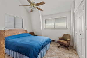 Bedroom featuring light carpet, vaulted ceiling, a ceiling fan, a baseboard heating unit, and a closet