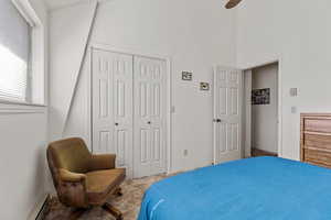 Bedroom with a baseboard radiator, carpet flooring, a closet, ceiling fan, and a high ceiling