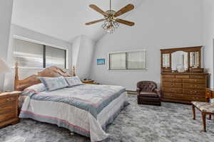 Bedroom with lofted ceiling, multiple windows, carpet, ceiling fan, and a baseboard heating unit
