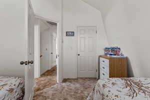 Bedroom with light colored carpet and lofted ceiling