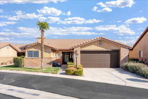 View of front facade with driveway, a tile roof, a garage, and stucco siding