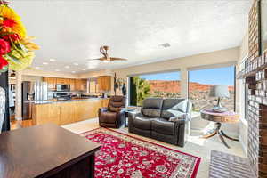 Living area with light carpet, ceiling fan, a textured ceiling, and recessed lighting