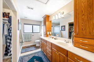 Bathroom with a walk in closet, double vanity, and a textured ceiling
