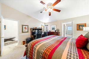 Carpeted bedroom featuring lofted ceiling and a ceiling fan
