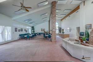Carpeted living room with ceiling fan and vaulted ceiling