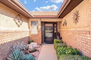 Property entrance with brick siding, stucco siding, and a tile roof