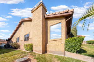 View of property exterior with a yard, stucco siding, and a tile roof
