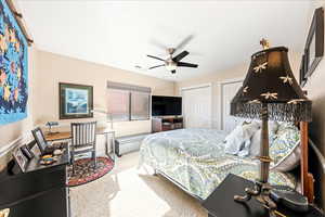 Bedroom featuring light carpet, ceiling fan, and two closets