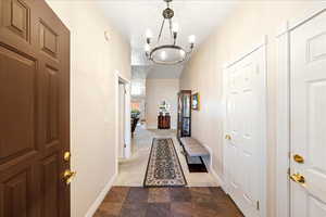 Corridor with dark colored carpet, a chandelier, and stone finish flooring