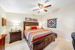 Bedroom featuring light colored carpet, a textured ceiling, and ceiling fan