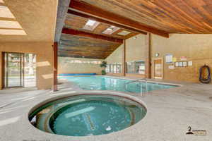 View of pool with a hot tub and a skylight