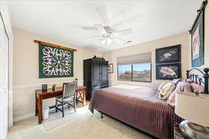 Bedroom with a closet, a ceiling fan, a textured ceiling, an office area, and light colored carpet
