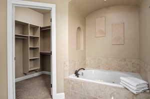 Bathroom featuring a garden tub and a walk in closet