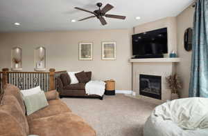 Carpeted living room with ceiling fan, a fireplace, and recessed lighting