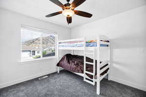 Bedroom with dark carpet, ceiling fan, and a mountain view