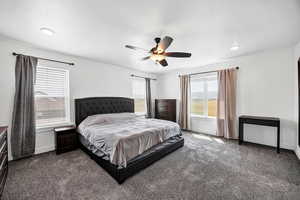Bedroom with dark colored carpet, ceiling fan, and a textured ceiling