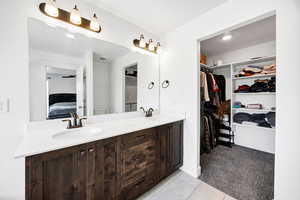 Ensuite bathroom with light carpet, double vanity, a spacious closet, and light tile patterned flooring