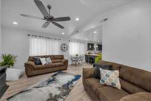 Living area with light wood-style floors, vaulted ceiling, ceiling fan, and recessed lighting