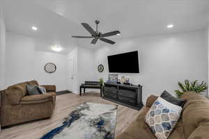 Living area featuring light wood-style floors, ceiling fan, lofted ceiling, and recessed lighting