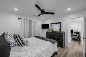 Bedroom with light wood-style floors, a ceiling fan, and recessed lighting