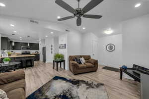 Living room featuring light wood-style flooring, vaulted ceiling, recessed lighting, and a ceiling fan