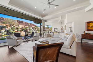 Living area with a raised ceiling, ceiling fan, hardwood / wood-style flooring, expansive windows, and recessed lighting