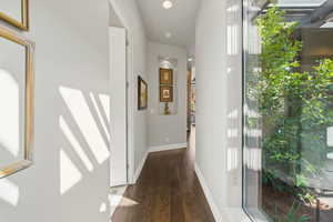 Hallway with plenty of natural light, recessed lighting, and dark wood finished floors