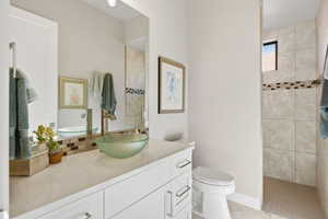 Full bath with vanity, walk in shower, light tile patterned flooring, and tasteful backsplash
