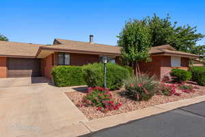 Ranch-style house featuring a shingled roof, driveway, brick siding, and a garage