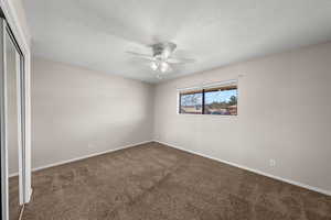 Unfurnished bedroom featuring a closet, carpet flooring, a textured ceiling, and a ceiling fan