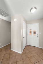 Foyer featuring a textured ceiling and light tile patterned floors
