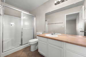 Full bath featuring vanity, a shower stall, and dark tile patterned floors