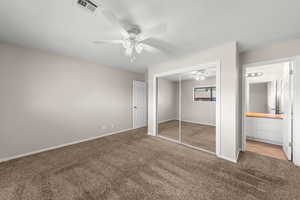 Unfurnished bedroom featuring carpet flooring, a closet, ceiling fan, connected bathroom, and a textured ceiling
