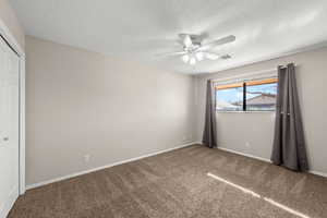 Unfurnished bedroom featuring a closet, carpet flooring, ceiling fan, and a textured ceiling
