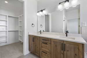 Full bathroom featuring double vanity, light carpet, and a spacious closet