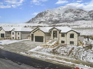 View of front of house featuring stone siding, driveway, a garage, and stucco siding