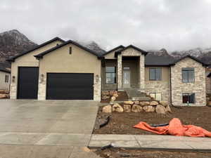 View of front of home with stone siding, driveway, a garage, and board and batten siding