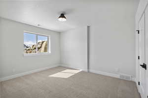 Unfurnished bedroom with light carpet and baseboards