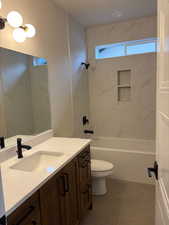 Bathroom with vanity, shower / bath combination, and dark tile patterned flooring