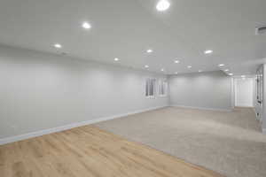 Finished basement with light wood-style floors and recessed lighting