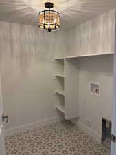 Laundry area with hanging lights, hookup for a washing machine, and a textured ceiling