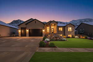 Enhanced photo (Landscaping not included) Single-story home with an attached garage, driveway, a lawn, a mountain view, and stone siding